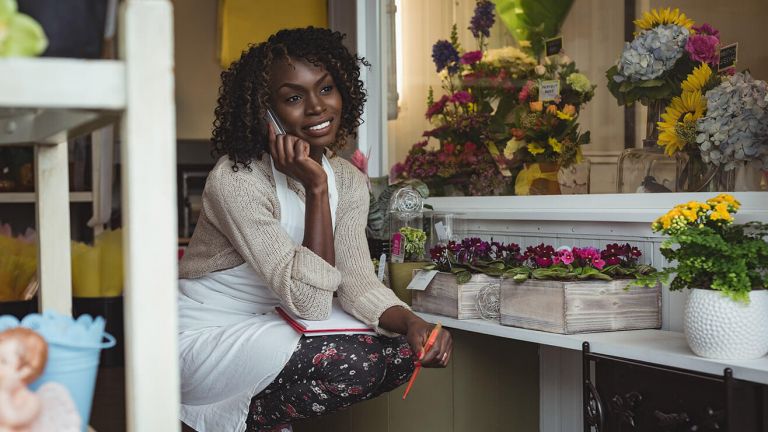 A florist wearing an apron takes a call on her mobile
